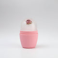 Hand holding a pink cylindrical container with a floral design on a white background
